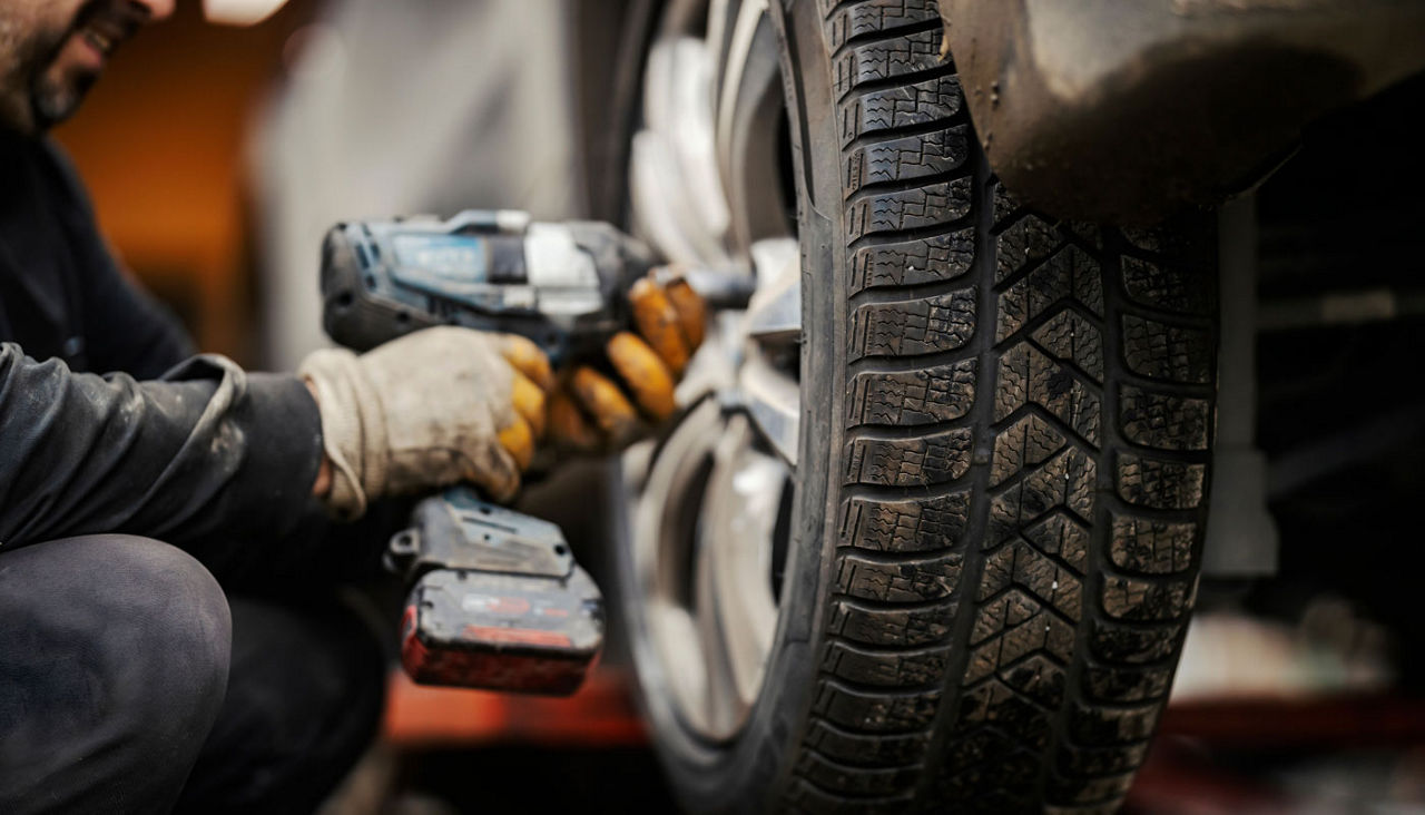 An auto mechanic installing winter tires on car at vulcanizing workshop.