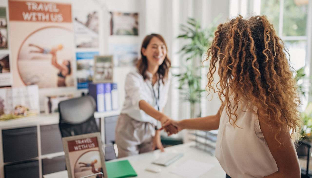 Woman shaking hands with a travel agent in office
