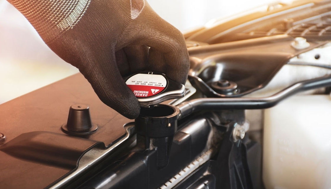 Mechanic hand is opening the radiator cap to check the coolant level of the car radiator