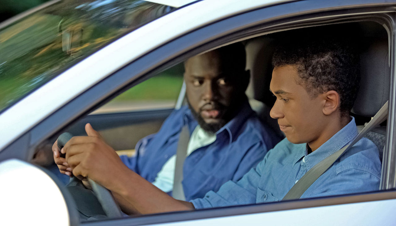 Father and son in car while teen is learning to drive