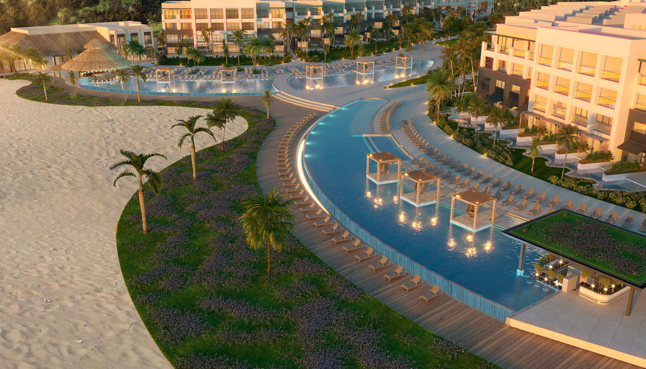 Arial view of a beach that is next to an amazing pool and hotel. 