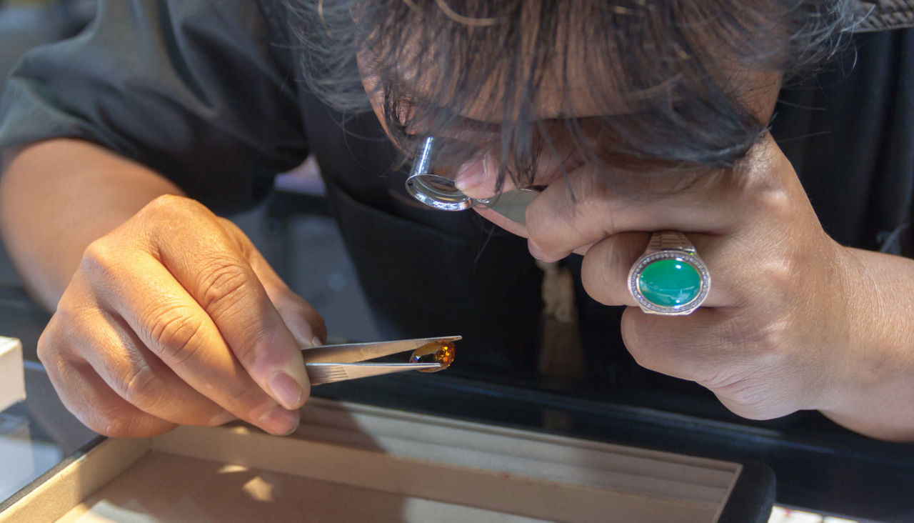 Male jeweler looking through a magnifier to check for flaws in a ruby. Experienced jeweller