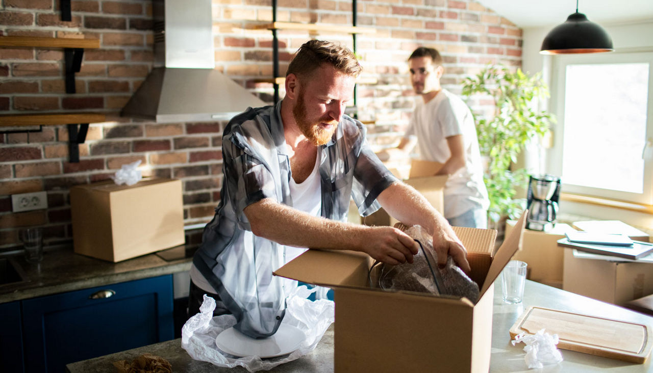 Young male gay couple unpacking boxes at new home