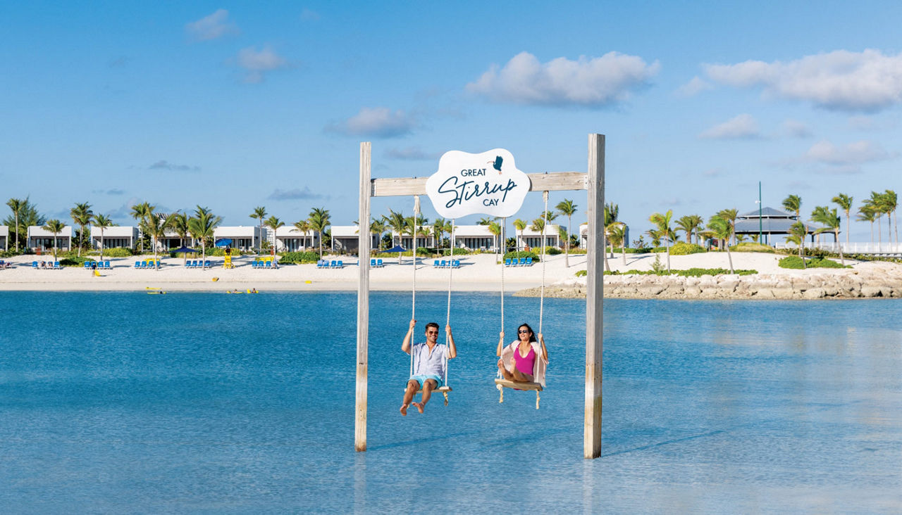 Carnival's Private Island Collection -- two people on a swing in the ocean.