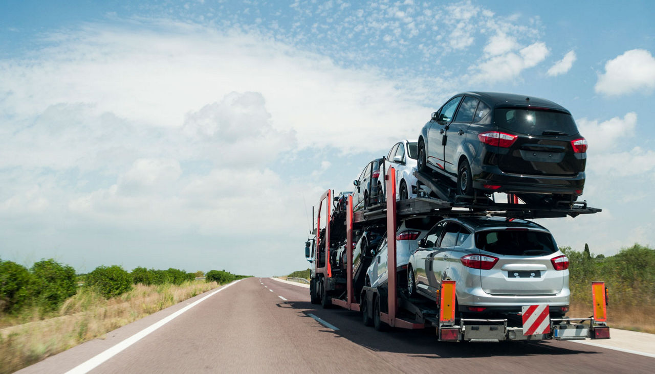 A car carrier hauling several cars down a highway.