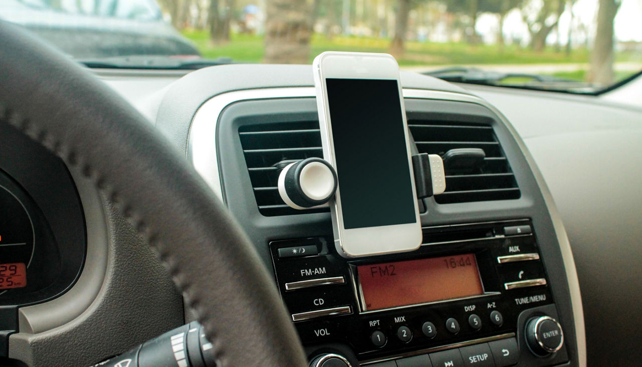 A smartphone charging in the car on the dashboard