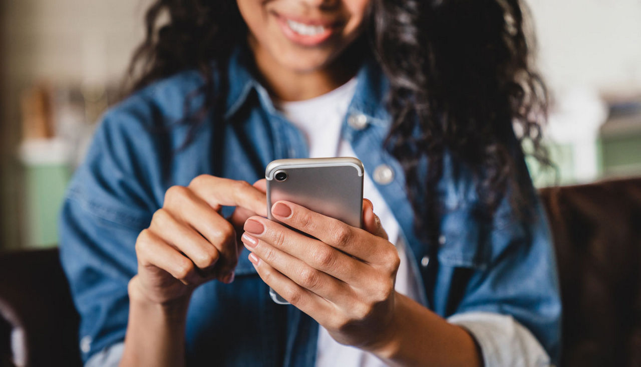 Smiling african american woman using smartphone at home, messaging or browsing social networks