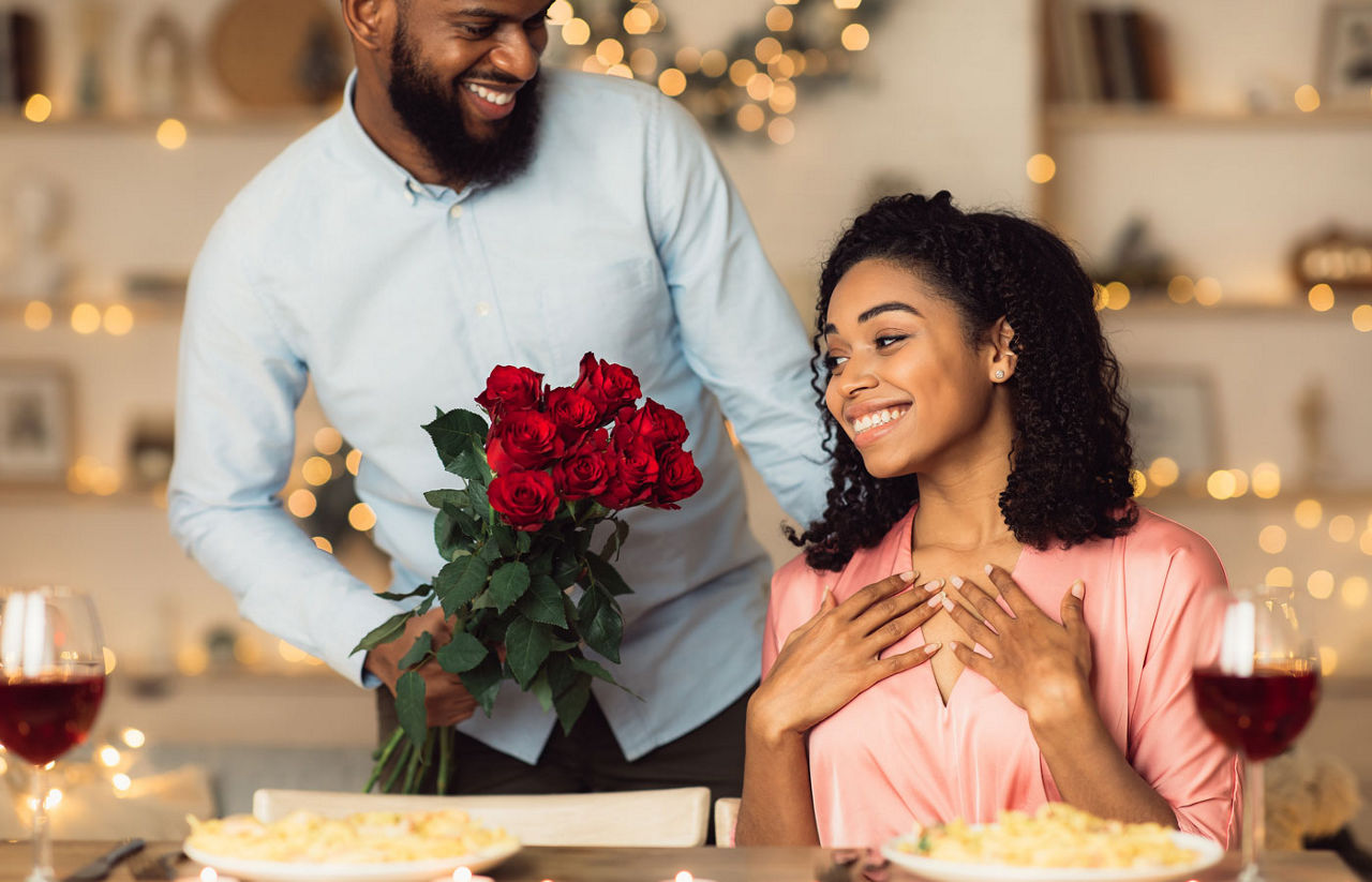 Young black man giving red roses to woman