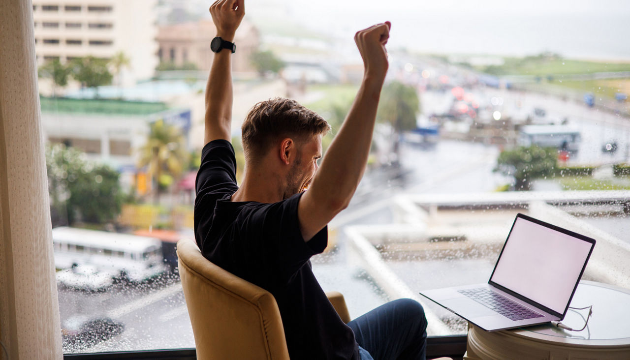 excited man watching sports on laptop in hotel room