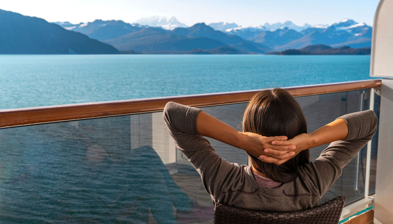 Tourist on cruise ship travel in Alaska relaxing looking at glaciers in Glacier Bay National Park, USA. Woman cruising Inside Passage enjoying stateroom balcony view of amazing nature landscape