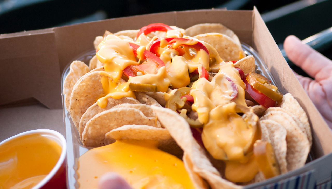 Nachos and cheese and peppers at a baseball game