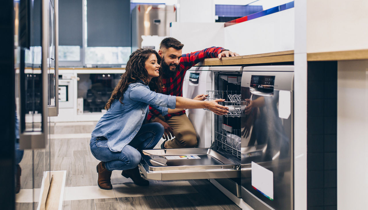 Young couple buying dishwasher in modern appliances store.