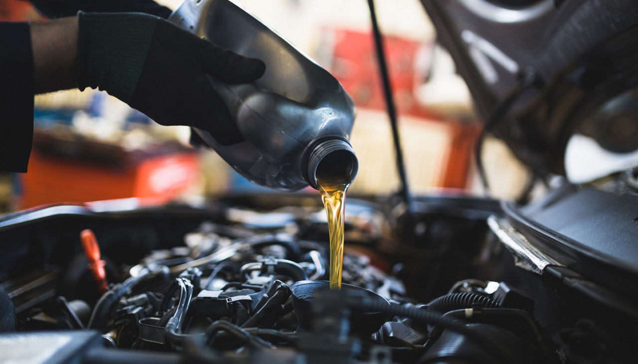 Close up of mechanic hands pouring liquid into car engine