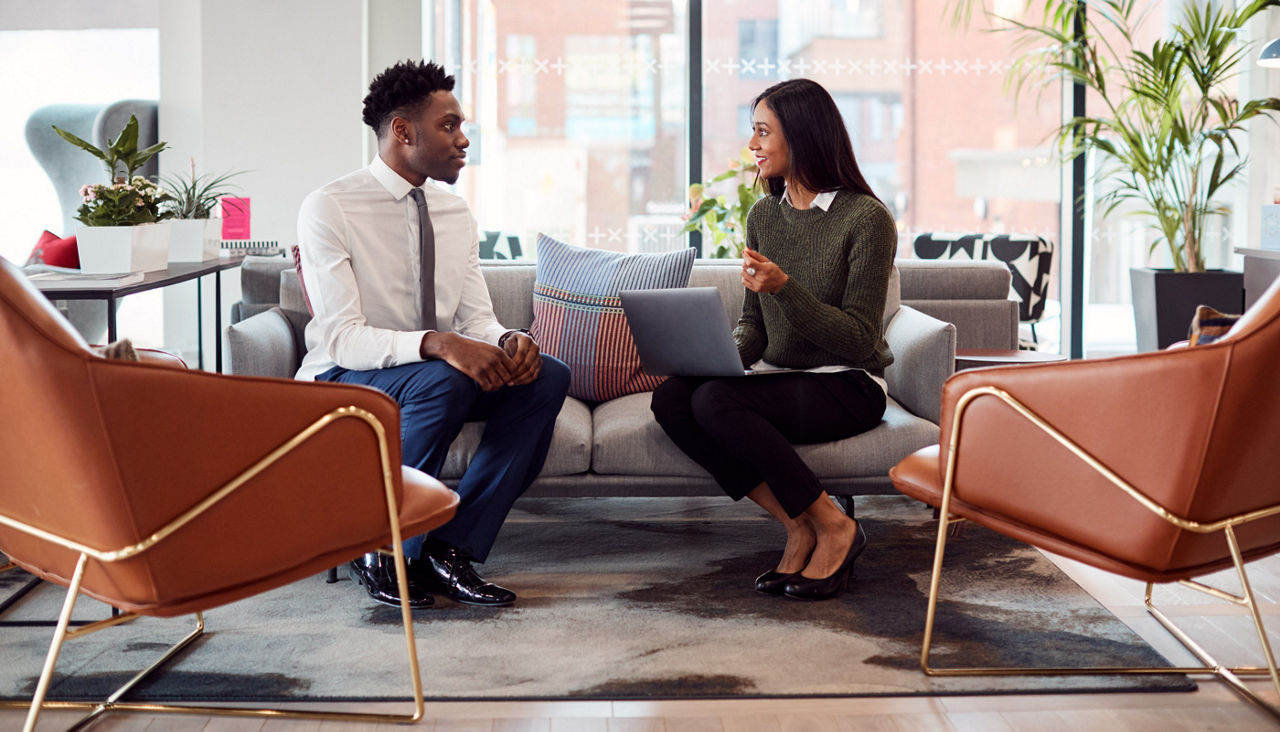 Businesswoman Interviewing Male Job Candidate In Seating Area Of Modern Office