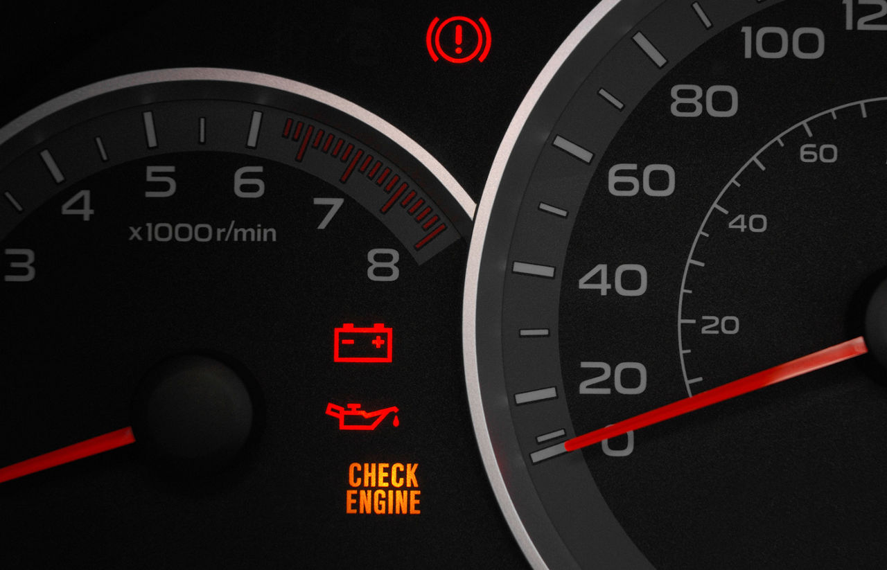 Close up on cluster with check engine light on, indicating a car failure