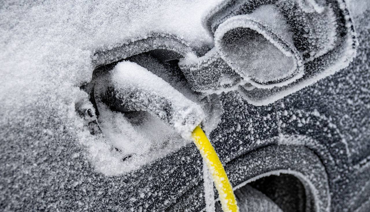 The electric car needs charging and is covered with ice