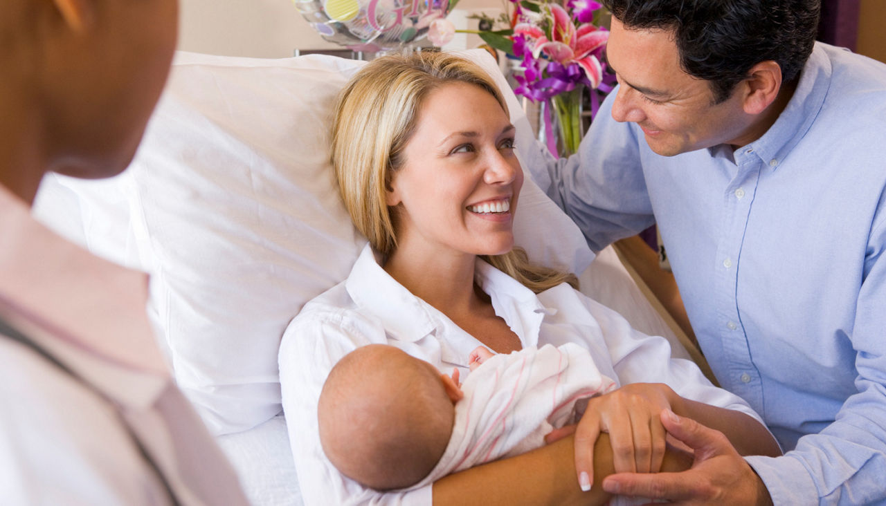 New parents with baby talking to doctor and smiling