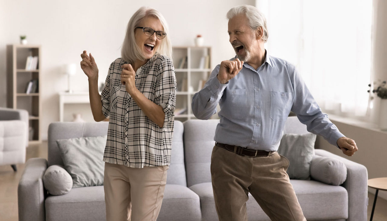 Happy mature couple laughing and dancing in living room