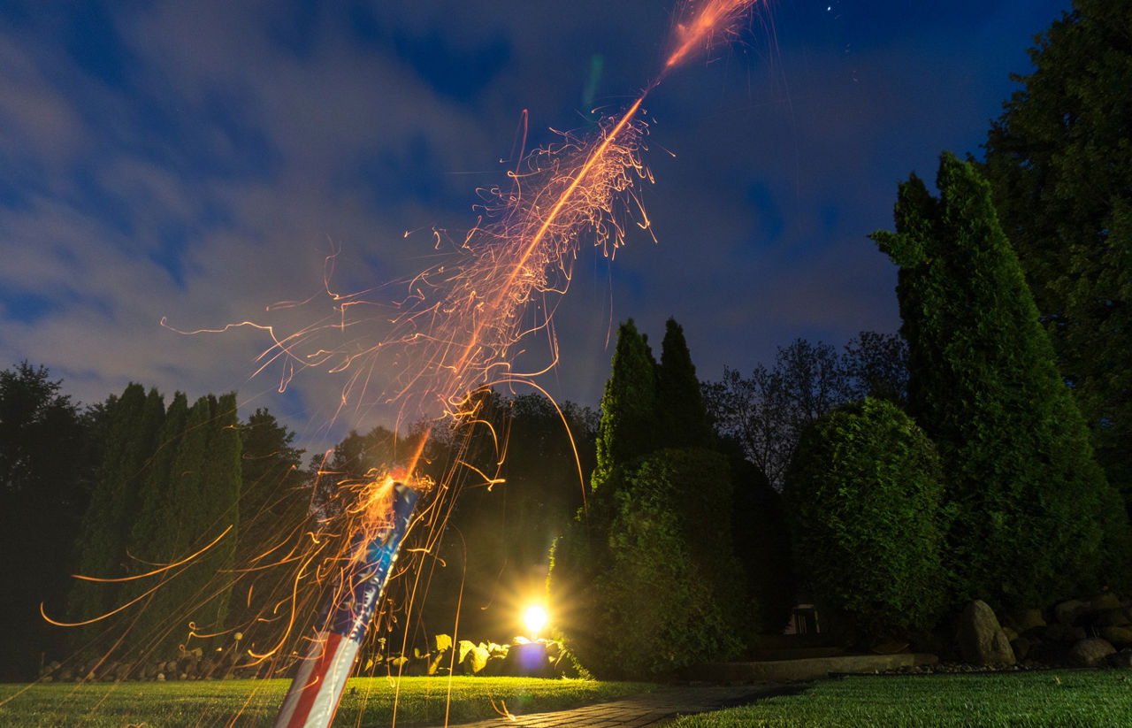Red, white and blue roman candle shoots fireworks into the night sky 