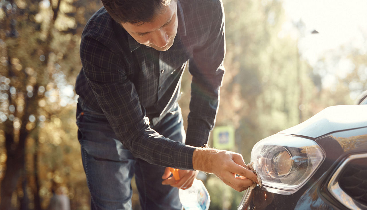 Man cleaning his headlights with a cleaner or kit
