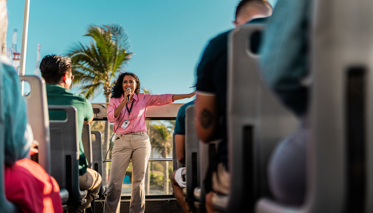 Mid adult tourist guide woman talking with tourist on tourist bus