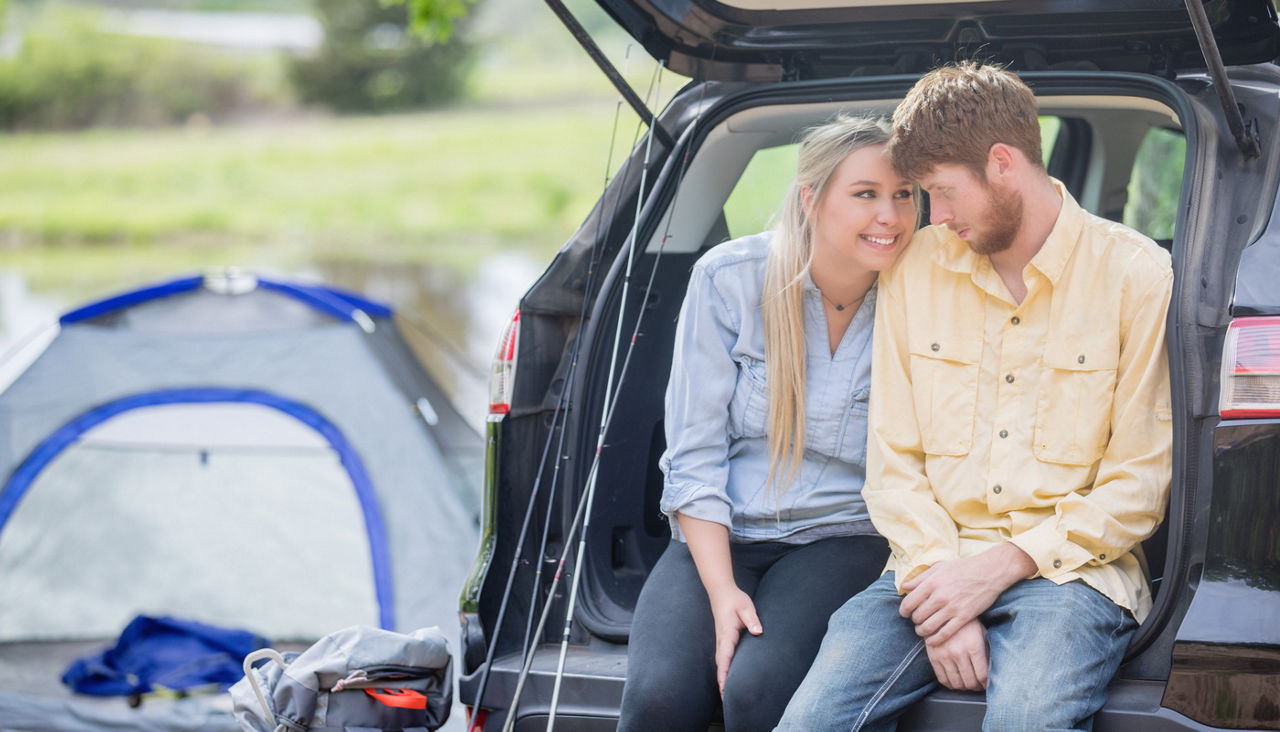 Young couple enjoy quality time together during camping trip, sitting on back of SUV