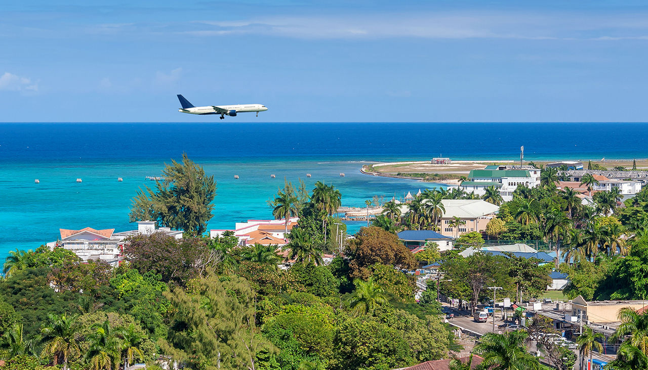 A passenger plane flies over the beach.