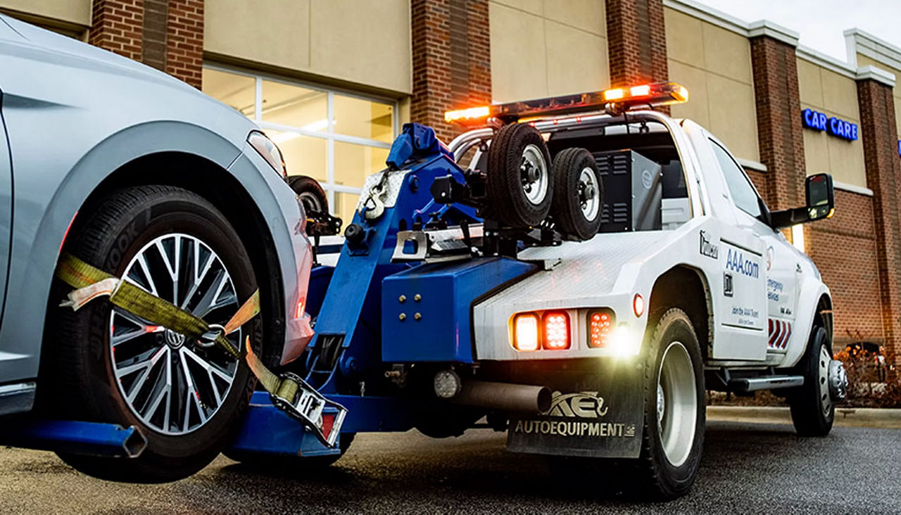 AAA tow truck towing a car to a car care facility.