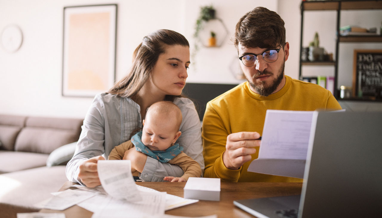 Young couple with baby going over taxes and bills at table