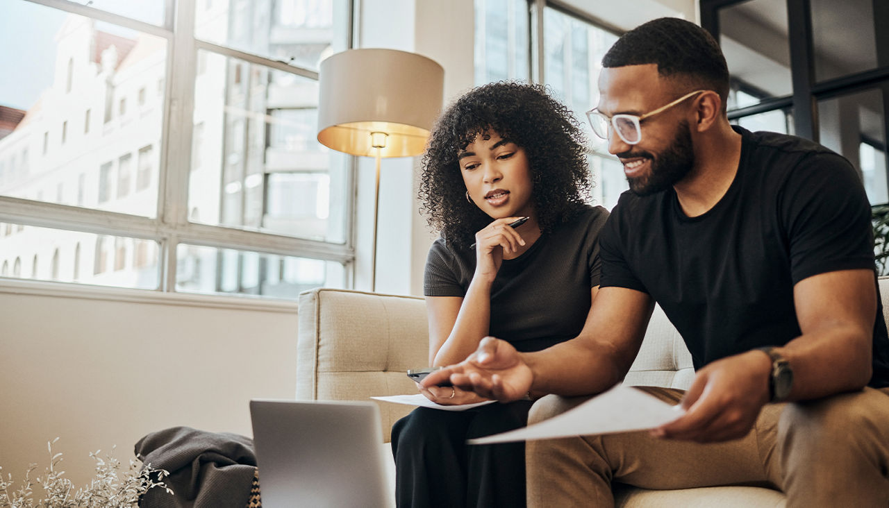 A couple looks over paper work together on their couch.