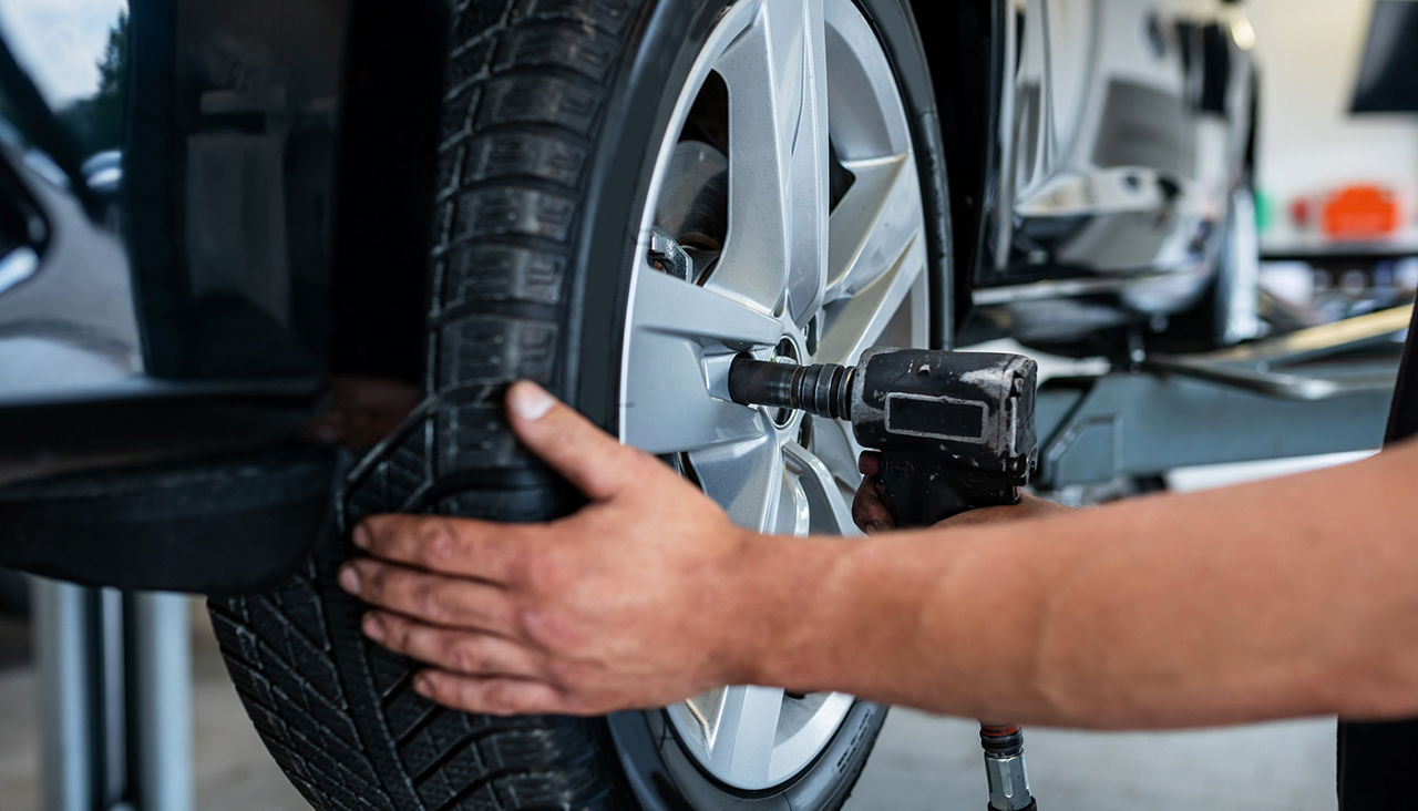 A mechanic changes a tire in a car repair shop.