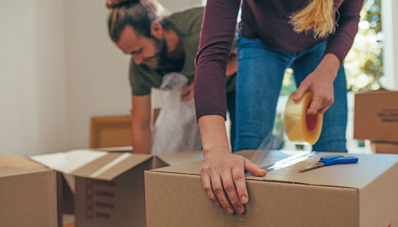 Close up of a woman applying adhesive tape on a packing box
