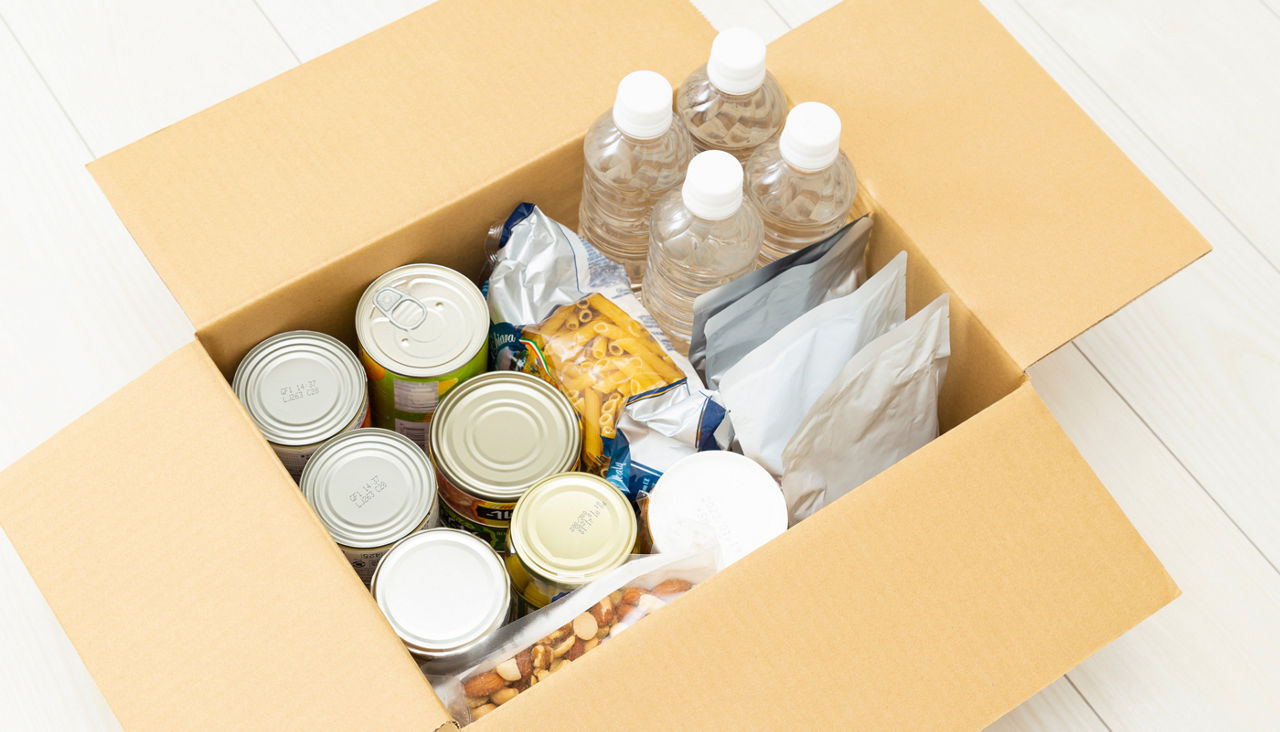 Cardboard box filled with storm supplies, food and water