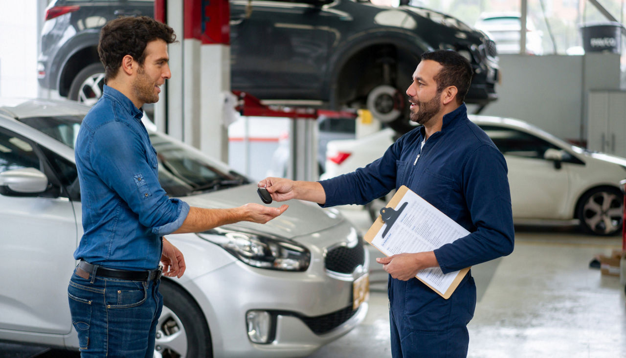 Man picking up his car at the auto repair shop and getting the keys from the mechanic