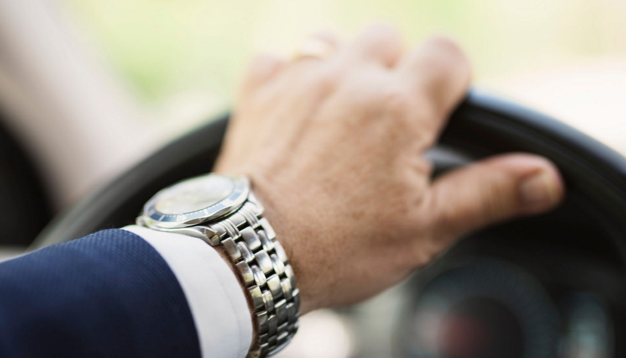Man's hand on steering wheel of car