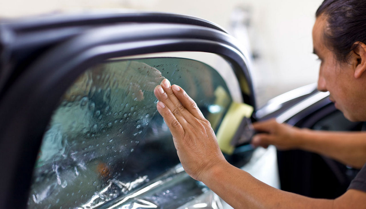 Man installing window tinting on car