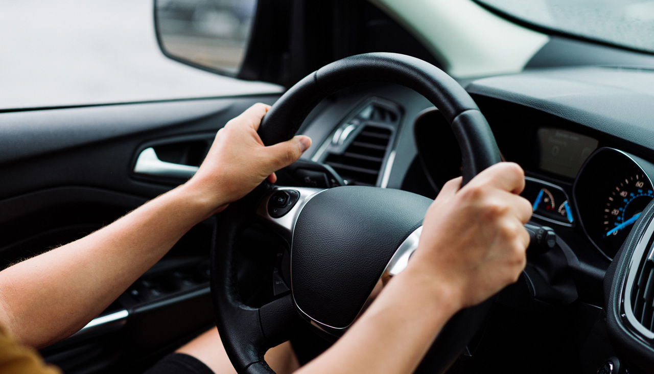 Women hands at 2 and 11 on the steering wheel of a car