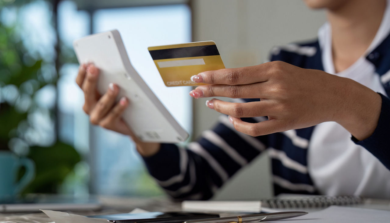 Young woman holding credit card and calculator
