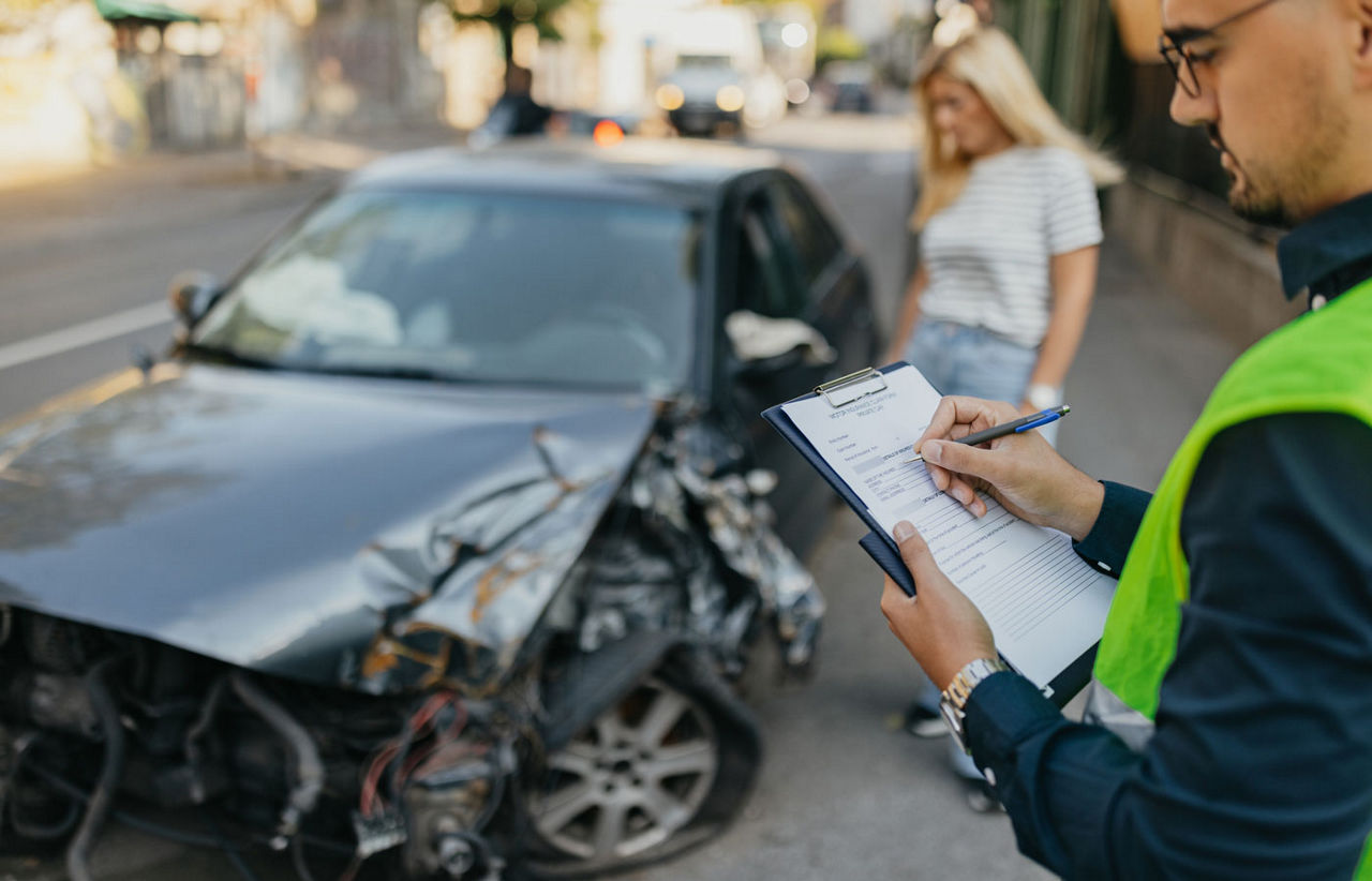 Man writing up a report of a wrecked car