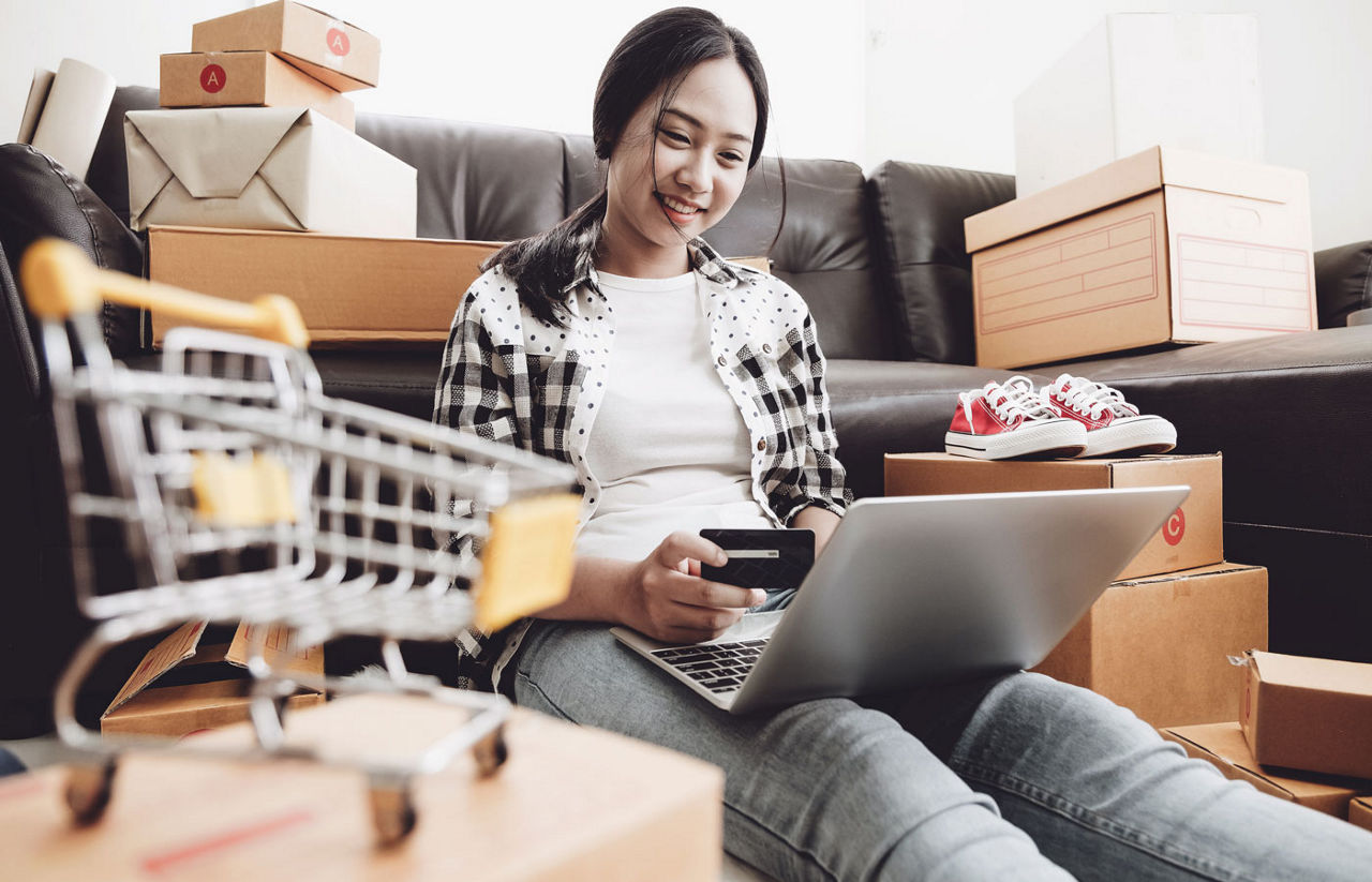 Young woman holding credit card and using laptop computer at home