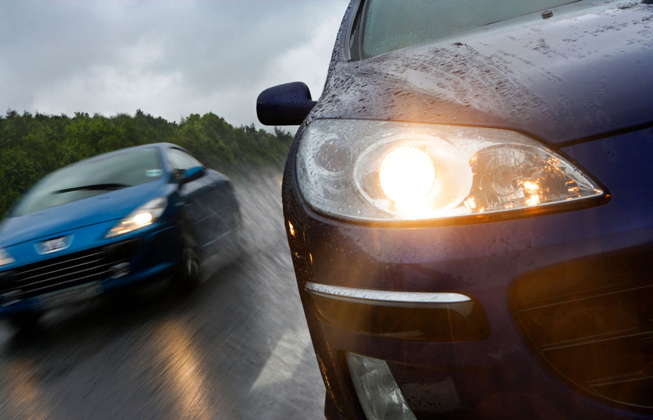 car driving in rain with headlights on