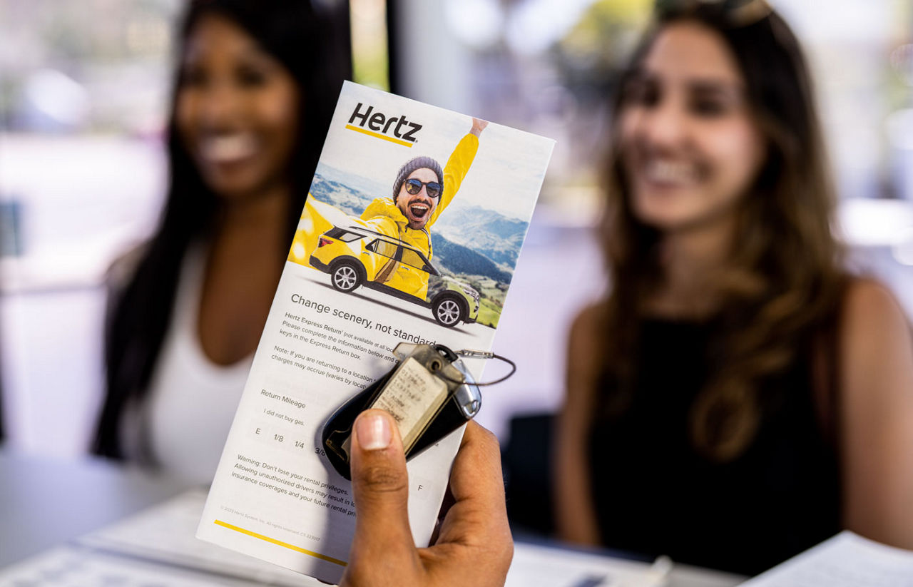 young women at Hertz counter renting a car