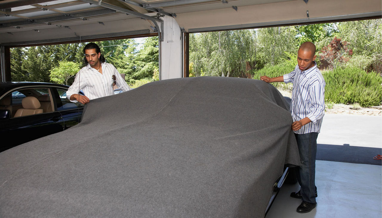 men covering a car in a garage