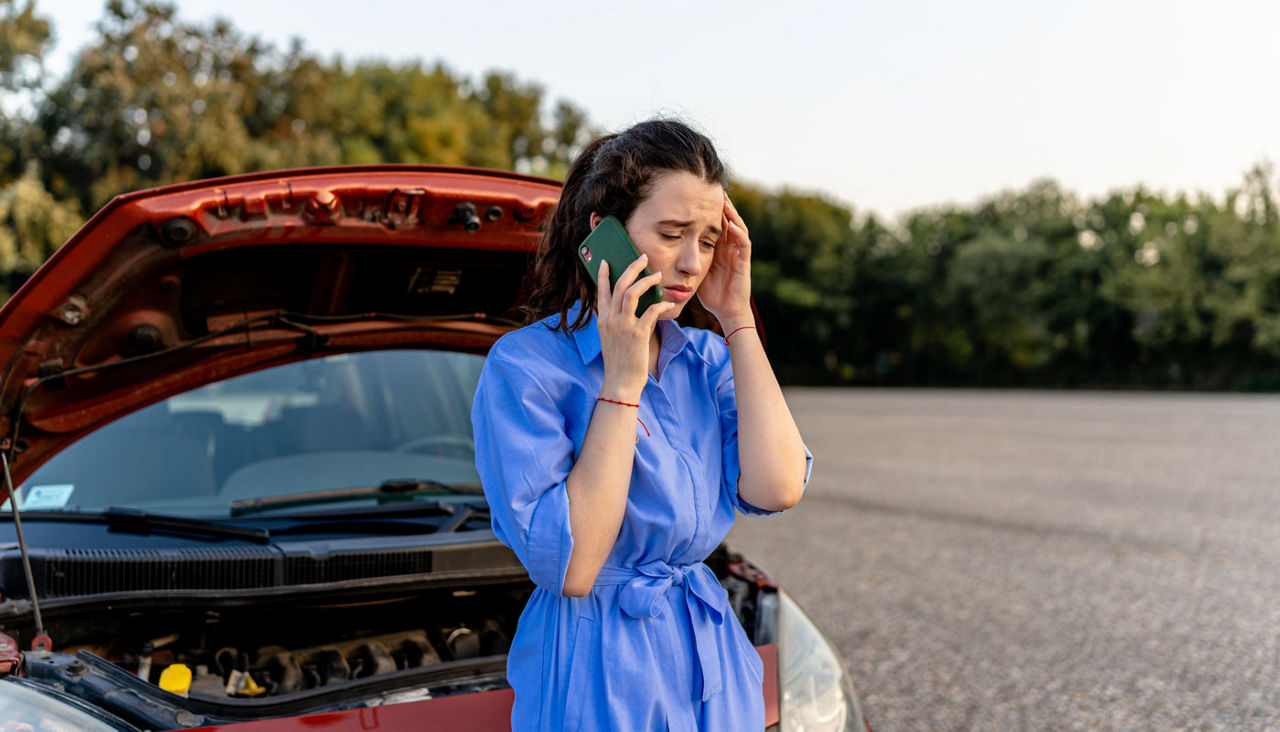 A young woman uses phone to call for roadside aid