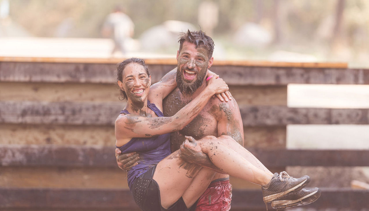 Man carrying woman in a Tough Mudder competition