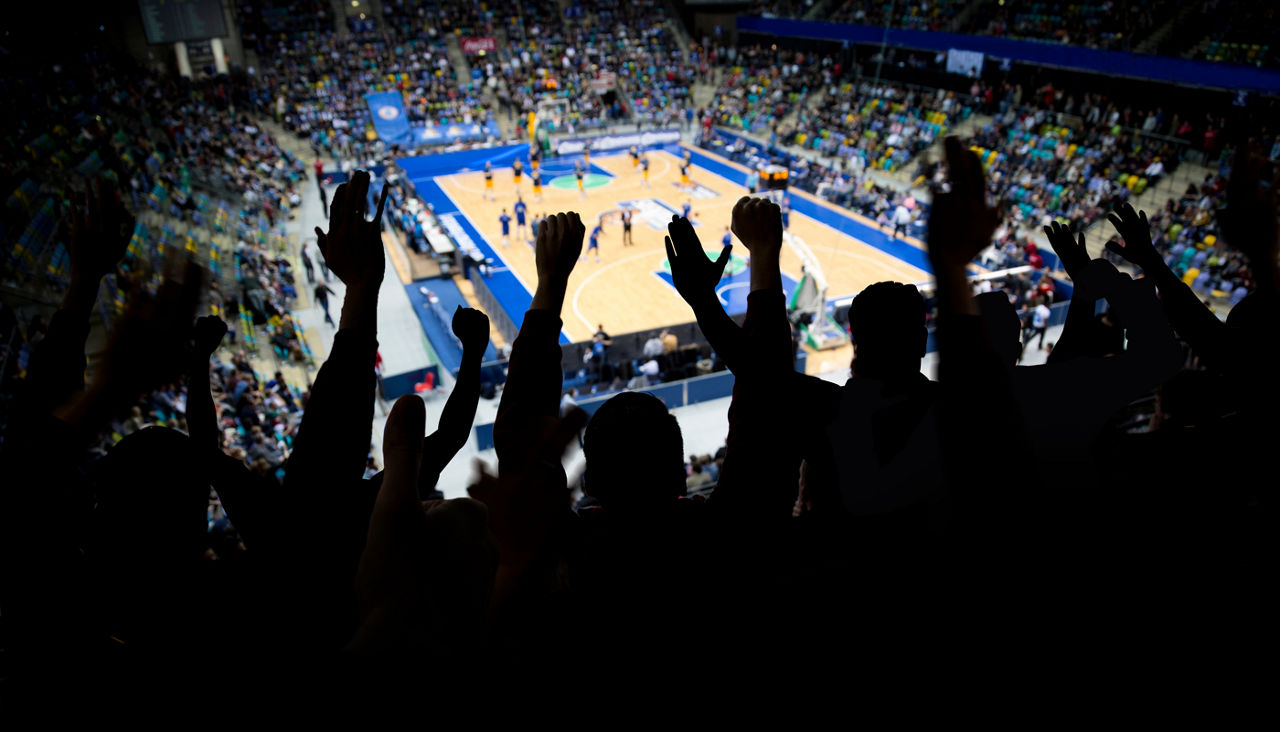 Silhouette of a group of spectators at a professional basketball game cheering for their team