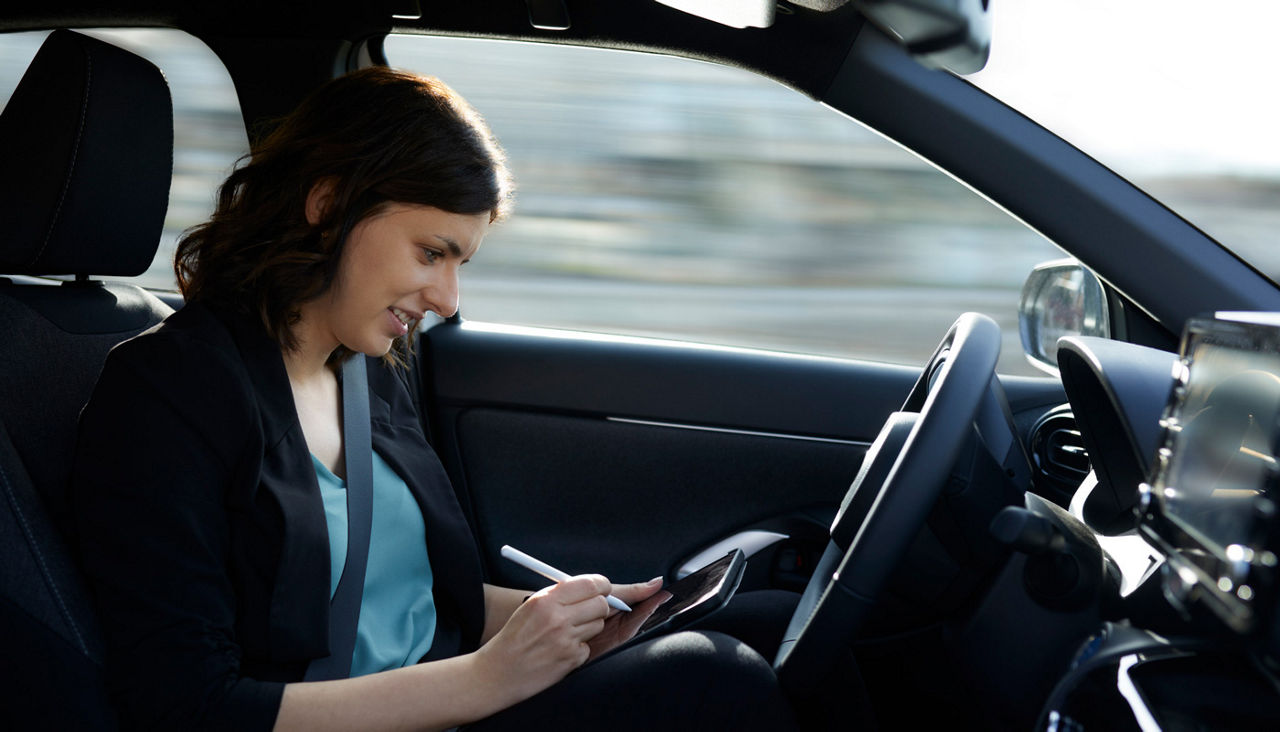 Smiling businesswoman using tablet PC in autonomous driving car