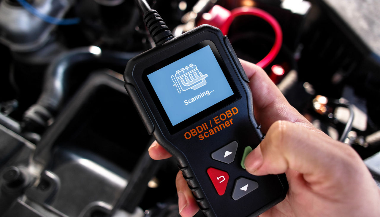 OBDII Scanner in use under the hood by auto mechanic for reading fault code of the car engine system