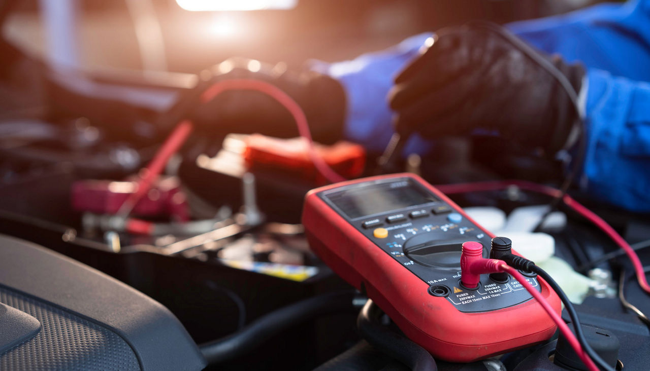 technician measure voltage of battery in the car at service station, Maintenance and repair