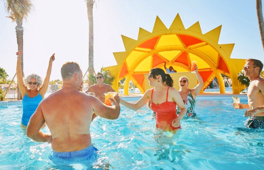 Group enjoying pool party under sunny pavilion on Celebration Key